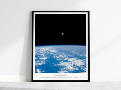 Framed Blue Marble NASA spacewalk wall art hanging on a white wall in a modern living room
