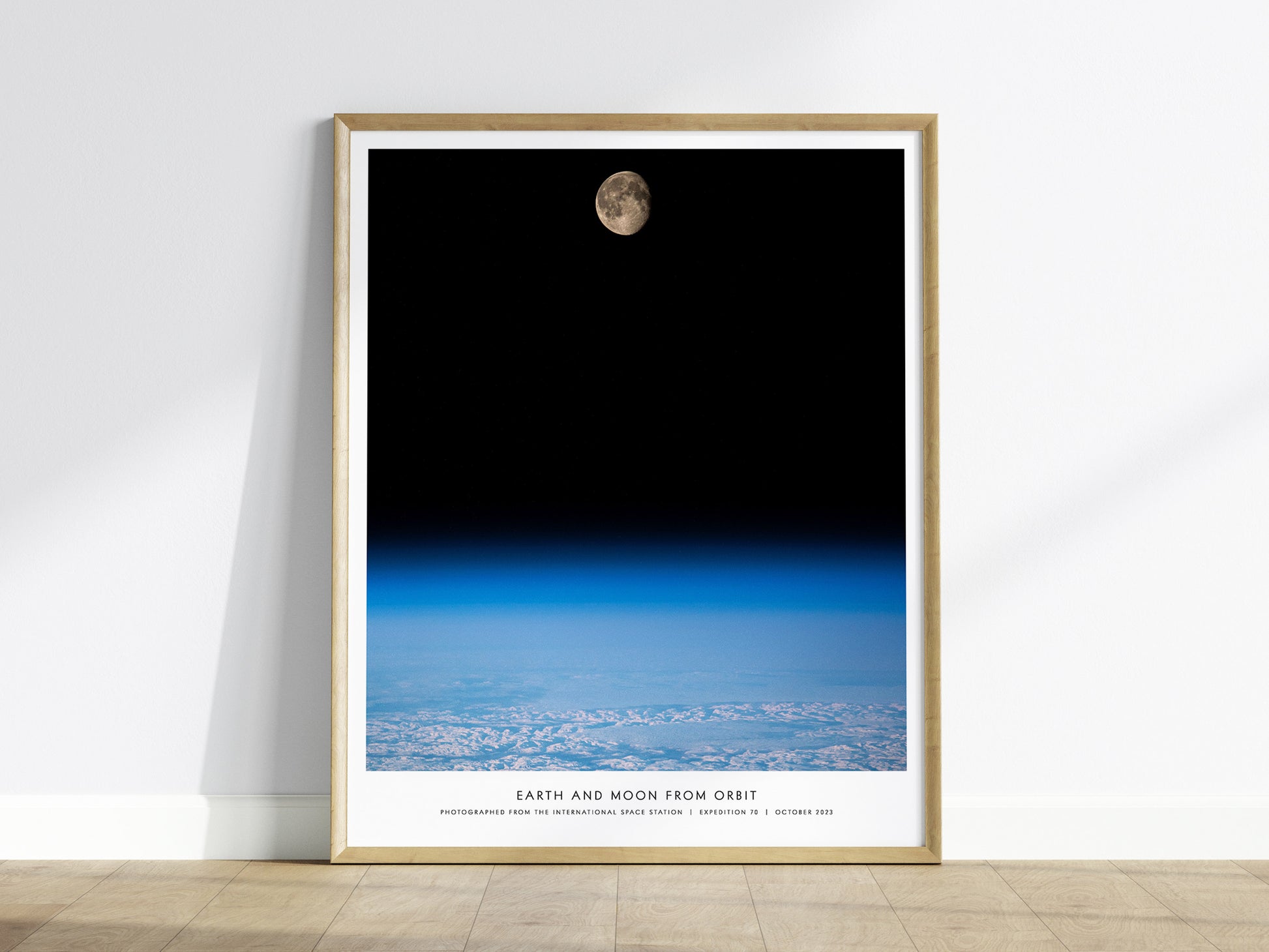 Framed Earth and Moon Orbit NASA wall art hanging on a white wall in a modern living room