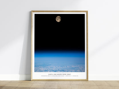 Framed Earth and Moon Orbit NASA wall art hanging on a white wall in a modern living room