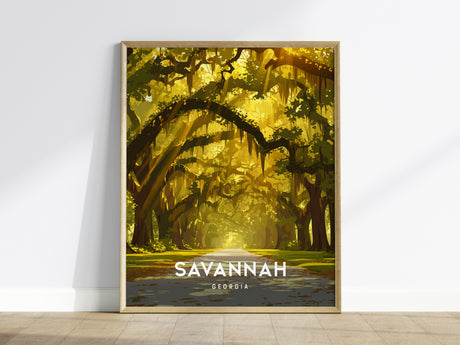 A framed poster on a wooden floor shows a tree-lined avenue draped in live oaks and Spanish moss, bathed in warm golden light. The text SAVANNAH GEORGIA is prominently displayed at the bottom.