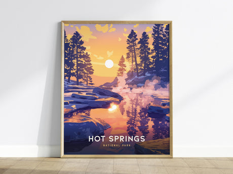 Framed artwork featuring a vibrant sunset over a tranquil lake, surrounded by silhouetted pine trees. The reflection of the colorful sky in the water adds a serene touch. The text reads Hot Springs National Park.