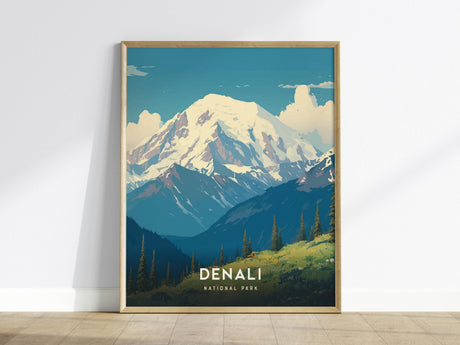 A framed poster of Denali National Park is displayed against a white wall. The artwork features snow-covered peaks under a blue sky, with green valleys and pine trees in the foreground. The word Denali is prominently visible.