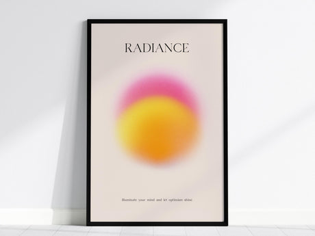 A framed poster titled RADIANCE features a vibrant pink and yellow gradient circle on a light background. The text at the bottom reads, Illuminate your mind and let optimism shine. The poster leans against a white wall.