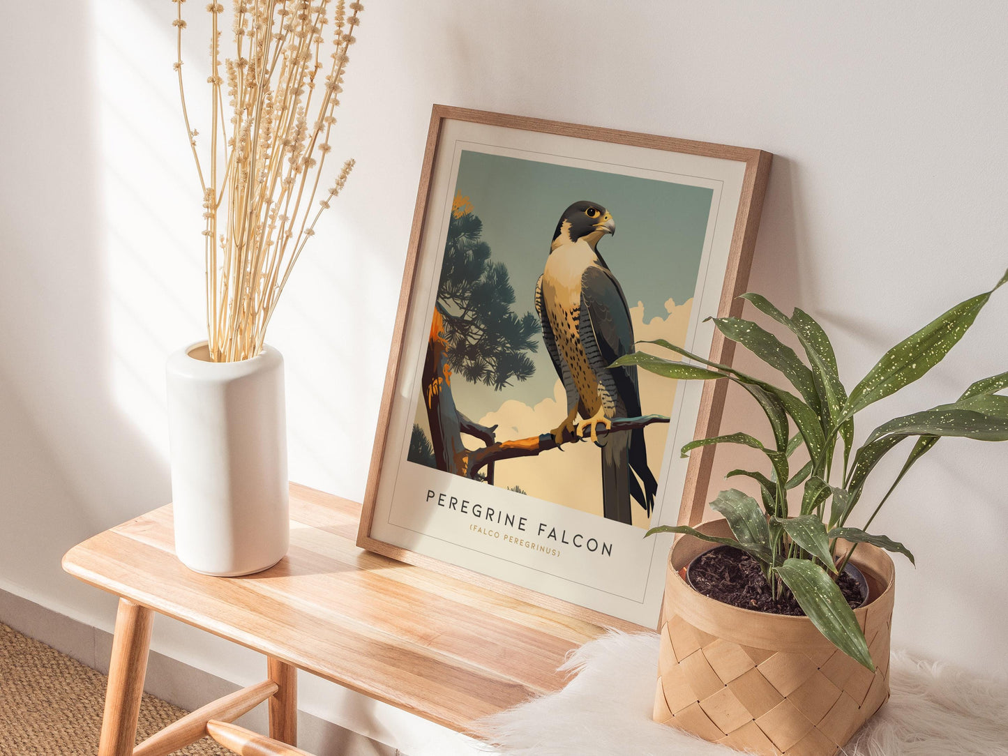 Framed artwork of a Peregrine Falcon on a wooden side table with plants and a vase.