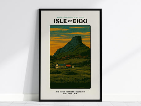 Framed poster featuring the Isle of Eigg with a vintage block print style. The image depicts the An Sgurr mountain, croft houses, and moorland under a colorful, textured sky.