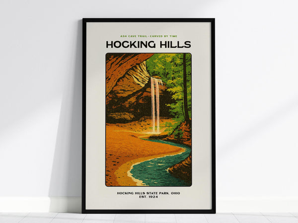 The image shows a framed poster depicting Hocking Hills, featuring a vibrant illustration of Ash Cave with a waterfall and lush greenery. This wall art captures the natural beauty of Ohios state park.