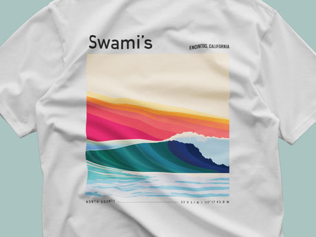 White t-shirt with a colorful wave design and 'Swami's' branding on a light blue background