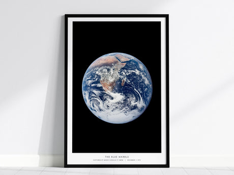 Framed Blue Marble Earth from space wall art hanging on a white wall in a modern living room
