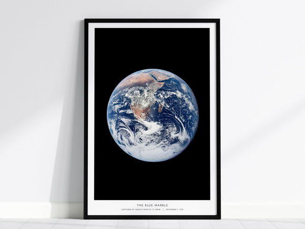 Framed Blue Marble Earth from space wall art hanging on a white wall in a modern living room
