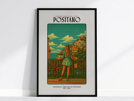 A framed poster of Positano showcases a woman in a dress gazing over a scenic view of colorful houses on a hillside, set against a vibrant blue sky with fluffy clouds. The artwork exudes a vintage travel vibe.