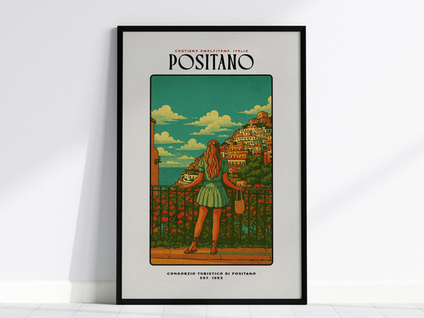 A framed poster of Positano showcases a woman in a dress gazing over a scenic view of colorful houses on a hillside, set against a vibrant blue sky with fluffy clouds. The artwork exudes a vintage travel vibe.