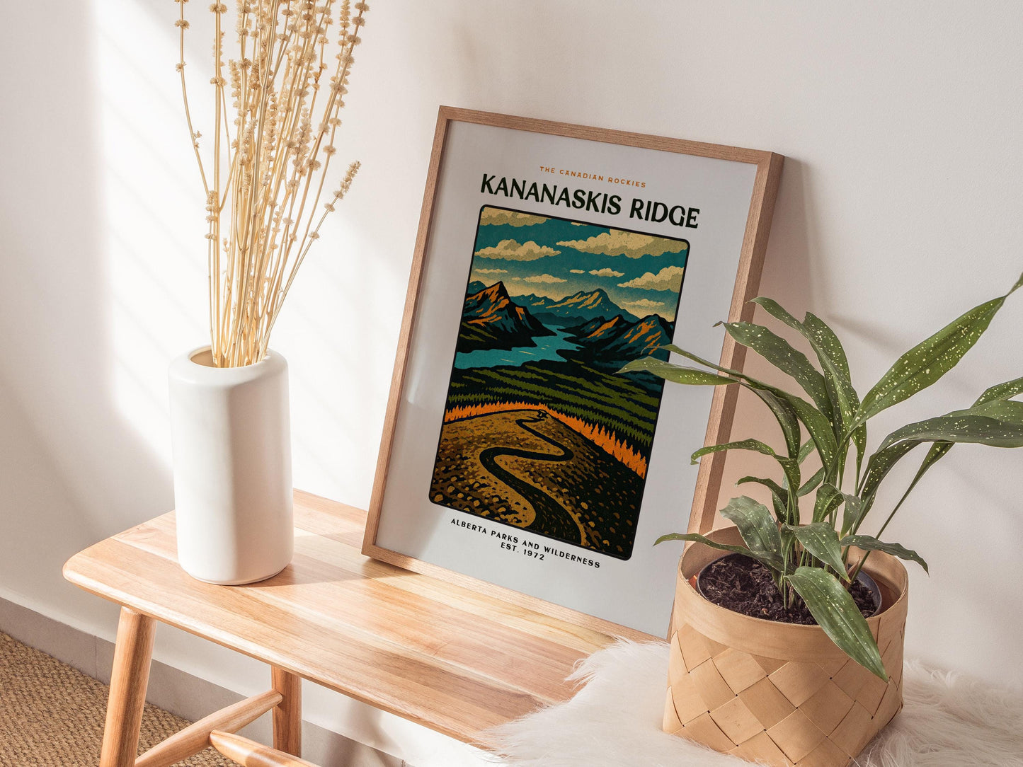 Framed poster of Kananaskis Ridge with decorative plants on a wooden table.