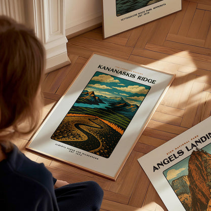 Person looking at a framed poster of Kananaskis Ridge on a wooden floor.