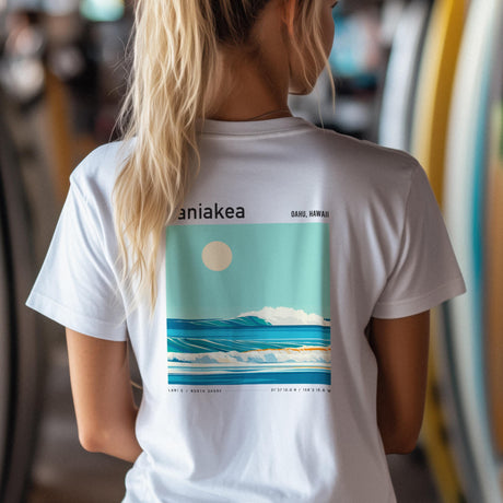 Person wearing a white Laniakea t-shirt with a graphic design on the back, featuring text and a landscape.