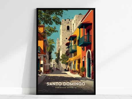 A framed poster depicts a vibrant street scene in Santo Domingo, featuring colorful colonial buildings with balconies, a stone tower, and lush greenery under a clear blue sky. The text reads Santo Domingo, Dominican Republic.