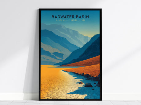 A framed poster of Badwater Basin in Death Valley National Park, featuring stylized cracked salt flats and layered mountain ranges in shades of blue, yellow, and orange. The image captures the essence of the desert landscape.