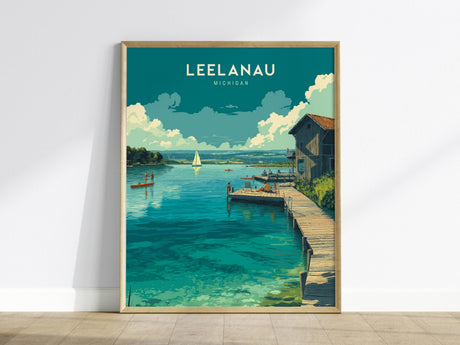 A framed poster of Leelanau, Michigan, depicts a serene lake scene with a rustic dock, a sailboat on calm water, and a house by the shore. The artwork features vibrant colors and a peaceful atmosphere.
