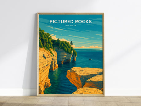 A framed poster of Pictured Rocks in Michigan shows colorful sandstone cliffs and lush greenery above the blue waters of Lake Superior. A small boat is visible on the water under a clear sky.