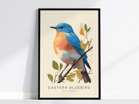 Illustrated print of an Eastern Bluebird with vibrant sky-blue wings and an orange breast, perched on a branch with green leaves. The artwork is displayed in a black frame against a light wall.