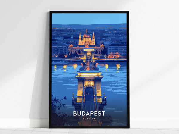 A framed poster showcasing Budapests illuminated Chain Bridge at night, with the city skyline and a prominent cathedral in the background. The artwork features vibrant blue and golden tones, capturing the bridges reflection in the river.