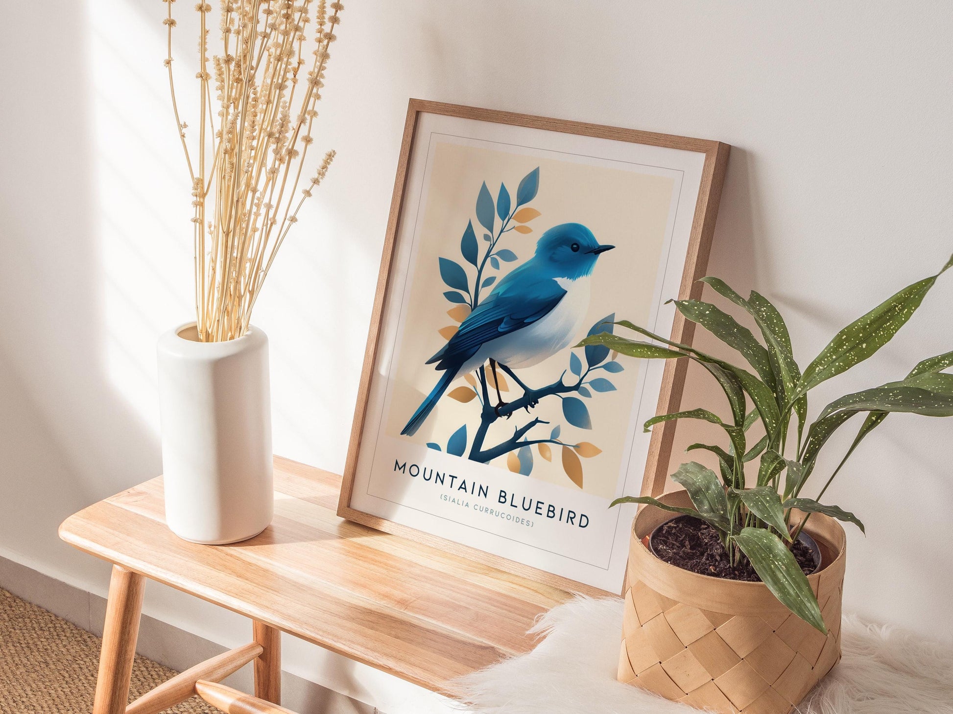 Framed artwork of a mountain bluebird on a wooden side table with plants.