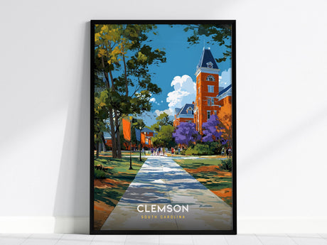 The image shows a framed poster featuring a vibrant illustration of Clemson, South Carolina. It depicts a historic clock tower surrounded by lush trees and colorful foliage, with a walkway leading through a scenic campus setting.
