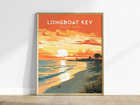 A framed poster depicting a vibrant sunset over a beach scene is propped against a wall. The image features an orange sky, white sun, gentle waves, and silhouettes of palm trees along the shore.