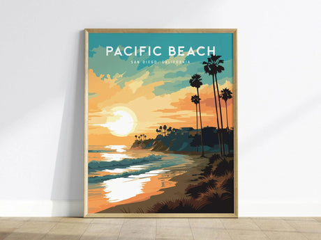 A framed poster of Pacific Beach in San Diego features a vibrant sunset over the ocean with palm trees silhouetted against the sky. The artwork captures the serene coastal vibe with warm colors and a modern design.