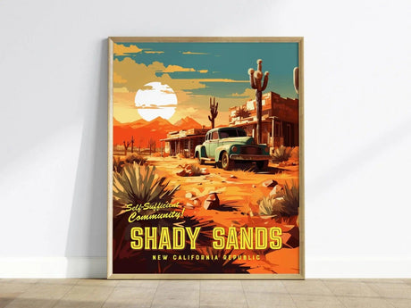A framed poster of Shady Sands features a vintage car on a dusty desert road with cacti and mountains under a setting sun. Bold text reads Self-Sufficient Community.