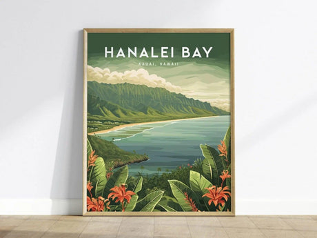 Framed artwork of Hanalei Bay, Kauai, Hawaii, showcasing a scenic view of lush mountains, a serene bay, and tropical foliage with orange flowers in the foreground. The poster leans against a white wall on a wooden floor.
