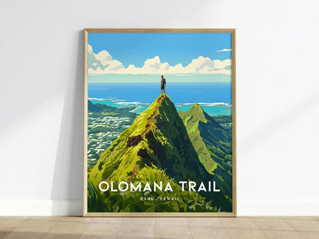 A framed poster of the Olomana Trail in Oahu, Hawaii, depicting a hiker standing atop a green peak with a scenic ocean view under a bright blue sky.