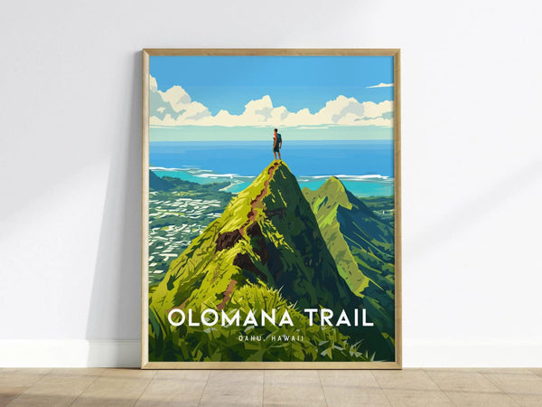 A framed poster of the Olomana Trail in Oahu, Hawaii, depicting a hiker standing atop a green peak with a scenic ocean view under a bright blue sky.
