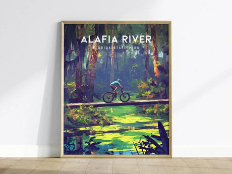 A vibrant poster featuring a mountain biker navigating a narrow wooden bridge over a serene creek in Alafia River State Park, surrounded by lush greenery and tall trees.