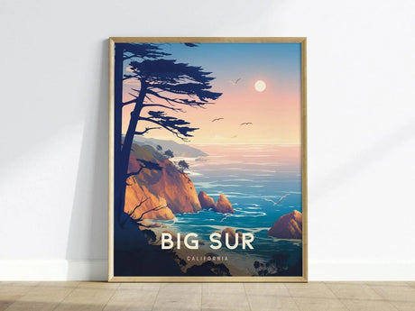 A beautifully framed poster of Big Sur, California, showcasing a tranquil coastal scene with cliffs, a setting sun, and a calm ocean. Silhouetted trees in the foreground enhance the serene atmosphere of this travel wall art.