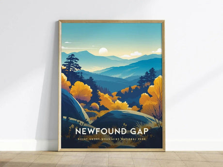 A framed poster of Newfound Gap showcases a stylized landscape of the Great Smoky Mountains, with layered blue ridgelines, vibrant yellow and orange foliage, and a winding road under a rising sun.