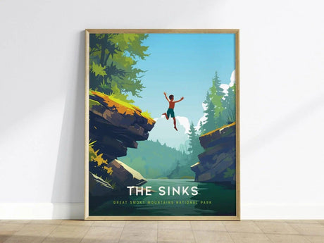 A framed poster depicting a person jumping into a river between two rocky cliffs, surrounded by lush green trees under a clear blue sky. The text reads The Sinks, Great Smoky Mountains National Park.