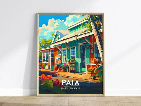 A vibrant poster depicting a colorful street scene in Paia, Maui, Hawaii, featuring quaint shops, lush greenery, and a bright blue sky. Framed artwork rests against a light wall.