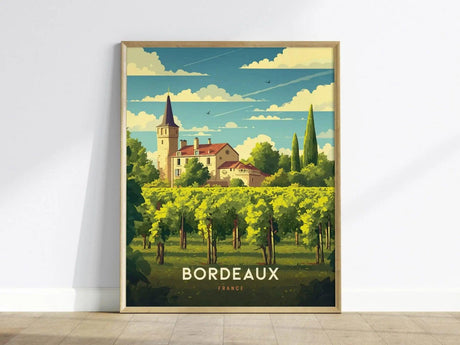Framed artwork depicting a picturesque Bordeaux vineyard with a chateau and tower under a blue sky. The words Bordeaux France are displayed at the bottom of the print.