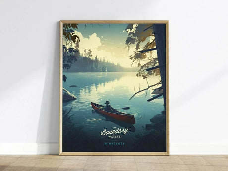 A framed poster depicting a serene lake scene with a person paddling a canoe at sunset, surrounded by trees and calm water reflections. Text reads The Boundary Waters Minnesota.