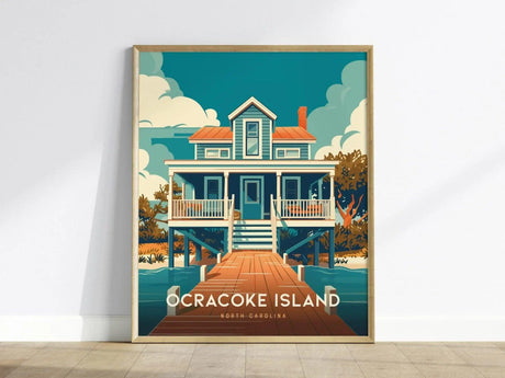 A framed poster depicting a stylized illustration of a waterfront house with a red roof, surrounded by trees and water, labeled Ocracoke Island, North Carolina.
