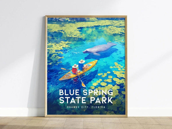 A framed poster shows two kayakers in colorful attire paddling on vibrant blue waters with a manatee nearby, surrounded by yellow lily pads.