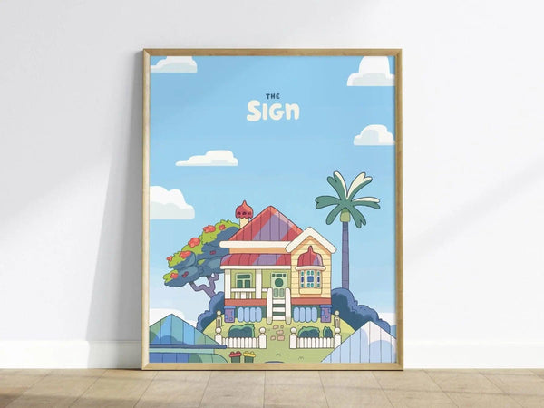 Framed wall art depicting a colorful house with a red roof, palm tree, and vibrant garden against a blue sky with clouds. The text The Sign is displayed above.