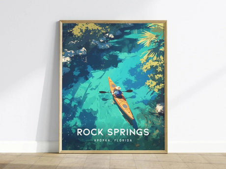 A framed poster displays an illustration of a kayaker paddling through clear blue waters surrounded by lush greenery, with the text Rock Springs, Apopka, Florida at the bottom.