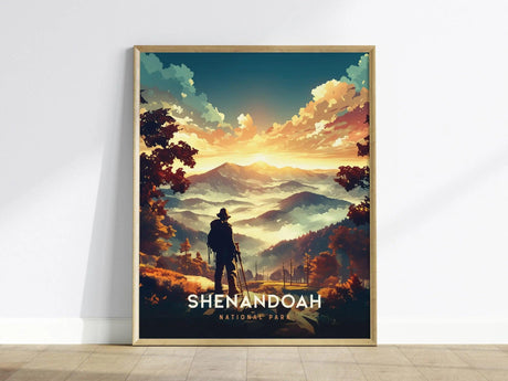 A framed poster of Shenandoah National Park showcases a vivid sunset over the Blue Ridge Mountains, with a silhouette of a hiker in the foreground. The artwork features rich colors and dramatic lighting, capturing the parks natural beauty.