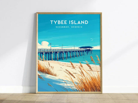 A framed poster of Tybee Island, Georgia, features a vibrant illustration of a fishing pier extending into the calm blue ocean. The foreground includes sandy dunes adorned with golden sea oats, capturing the coastal charm of the area.