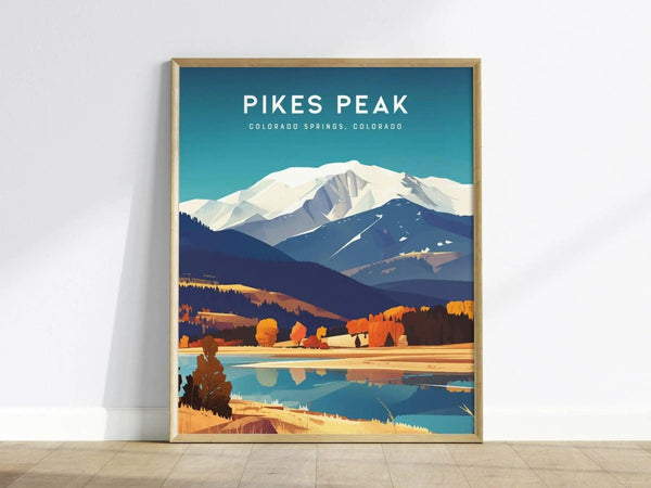 Framed poster of Pikes Peak features a stylized mountain scene with snow-capped peaks, colorful autumn trees, and a reflective lake. Text reads Pikes Peak, Colorado Springs, Colorado.