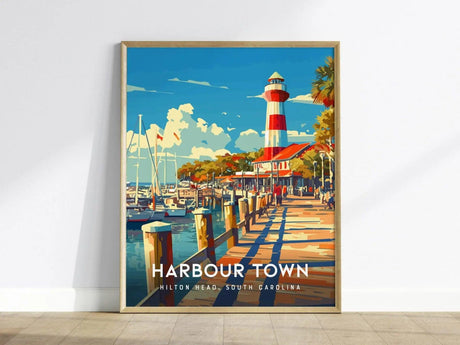 A framed poster features a vibrant illustration of the red-and-white striped Harbour Town Lighthouse, surrounded by boats and palm trees under a bright blue sky.