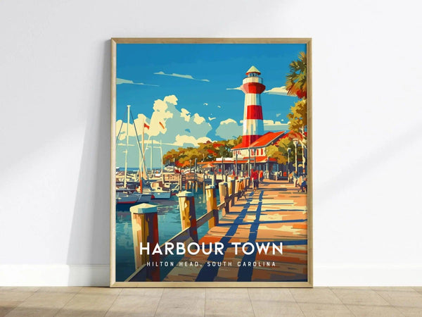A framed poster features a vibrant illustration of the red-and-white striped Harbour Town Lighthouse, surrounded by boats and palm trees under a bright blue sky.