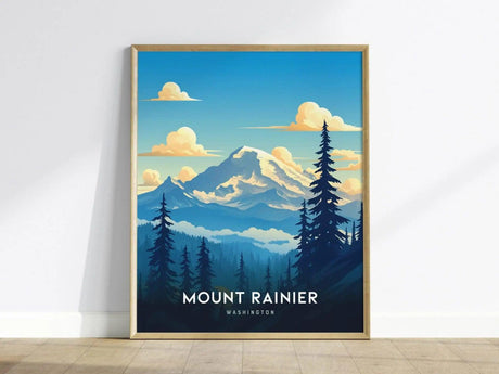 Framed poster of Mount Rainier featuring a stylized depiction of the mountain with a blue sky, fluffy clouds, and silhouetted evergreen trees, resting on a wooden floor.
