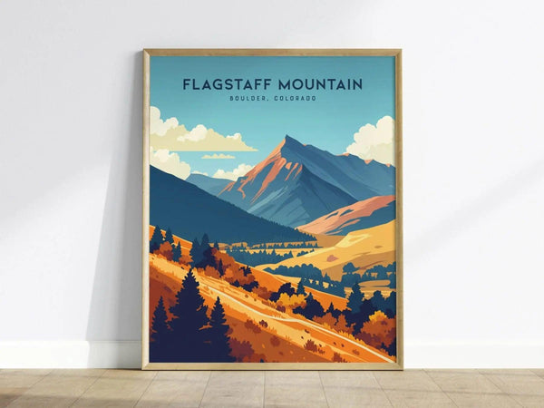 A framed poster of Flagstaff Mountain in Boulder, Colorado, featuring colorful, stylized illustrations of mountains, trees, and a vibrant sky, leaning against a white wall.